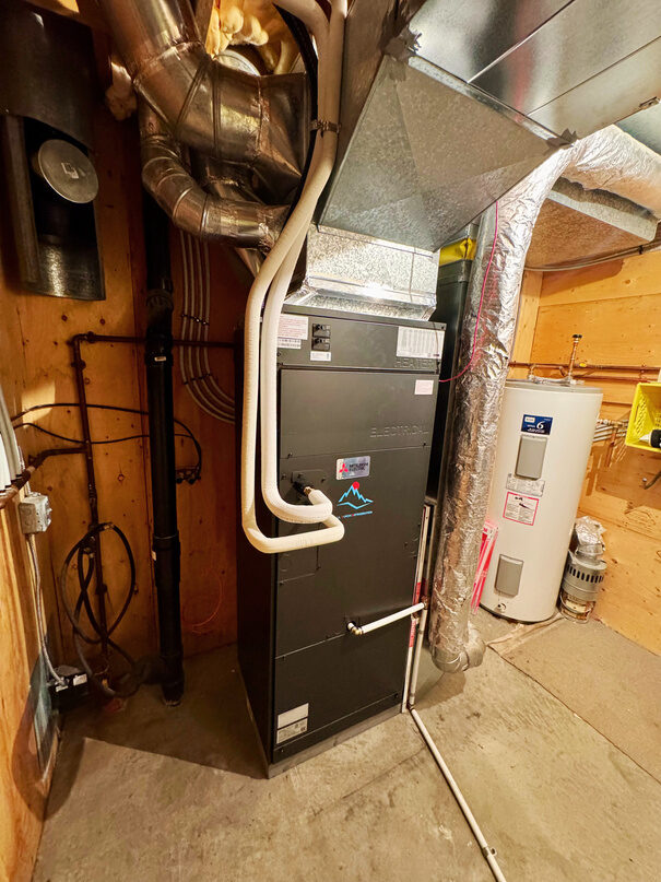 Air handler with sheet metal ductwork, insulated refrigerant lines and a water heater in a mechanical room